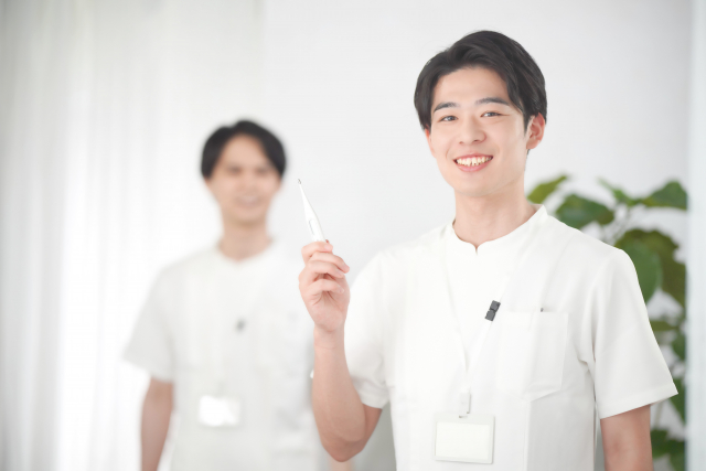 体温計をもつ男性看護師の画像